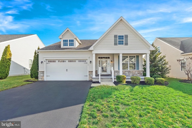 view of front of home with covered porch, a garage, and a front yard