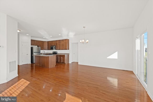 kitchen featuring a center island with sink, hanging light fixtures, a notable chandelier, wood-type flooring, and stainless steel appliances