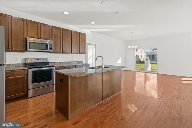 kitchen featuring sink, stainless steel appliances, a notable chandelier, pendant lighting, and a kitchen island with sink