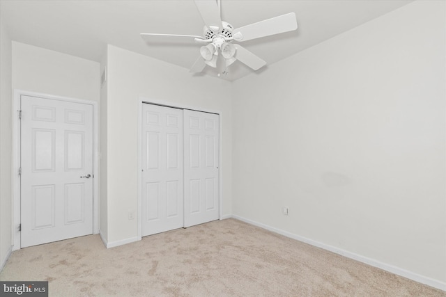 unfurnished bedroom featuring ceiling fan, light colored carpet, and a closet