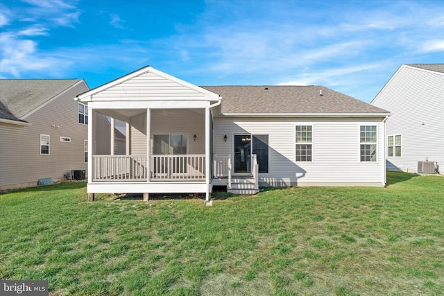 rear view of house featuring a yard, a sunroom, and central air condition unit