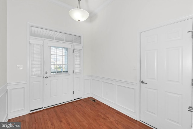 foyer entrance with crown molding and hardwood / wood-style floors