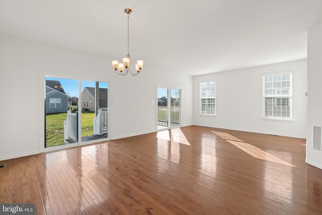 unfurnished room with wood-type flooring and a notable chandelier