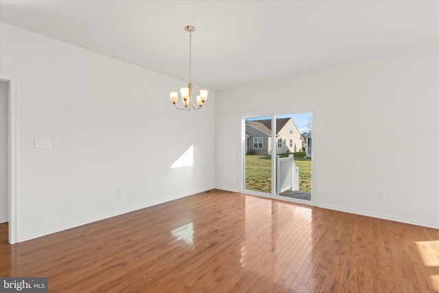 empty room with a chandelier and hardwood / wood-style flooring