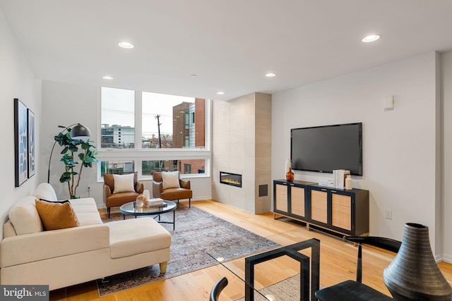 living room featuring a tiled fireplace and light hardwood / wood-style flooring