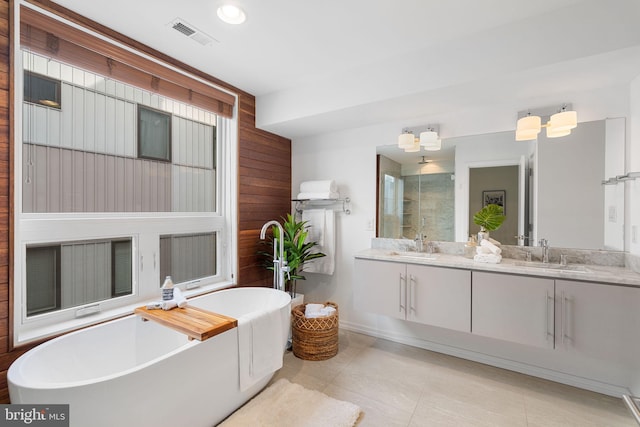 bathroom with wood walls, tile patterned flooring, vanity, and a bath