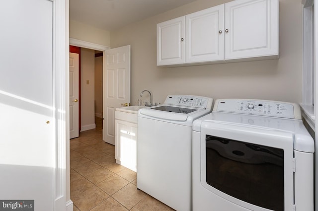 laundry room with cabinets, light tile patterned floors, sink, and washing machine and clothes dryer