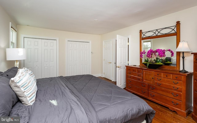 bedroom featuring hardwood / wood-style floors and two closets