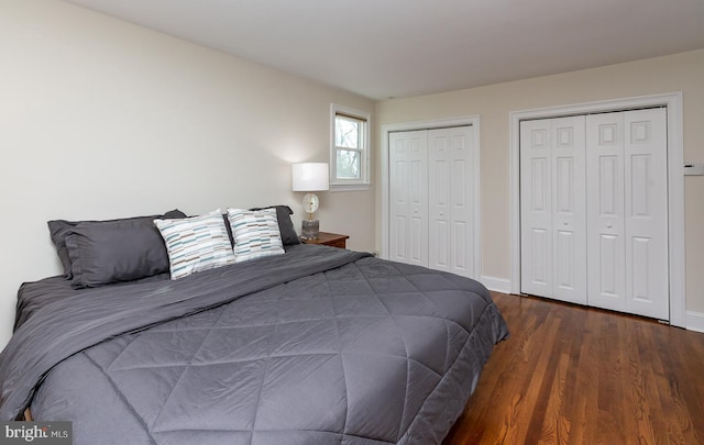 bedroom with dark hardwood / wood-style floors and two closets