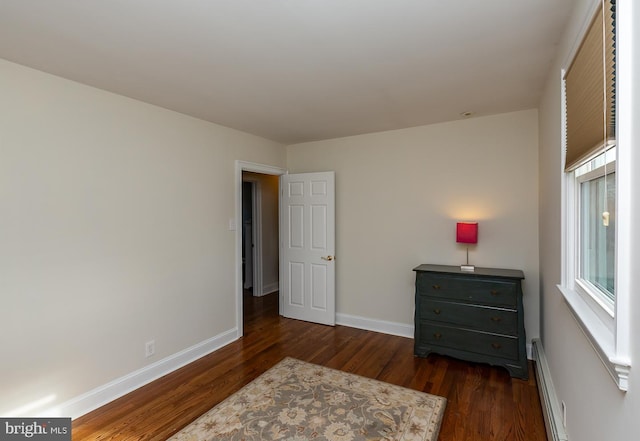 bedroom with dark wood-type flooring and a baseboard radiator