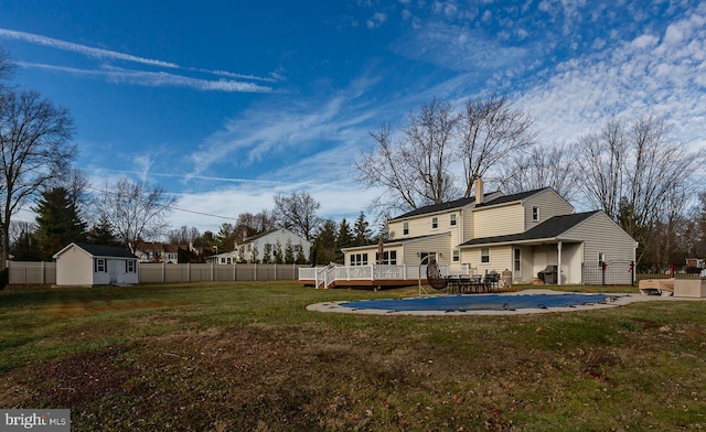 back of property featuring a lawn, a swimming pool side deck, and an outbuilding