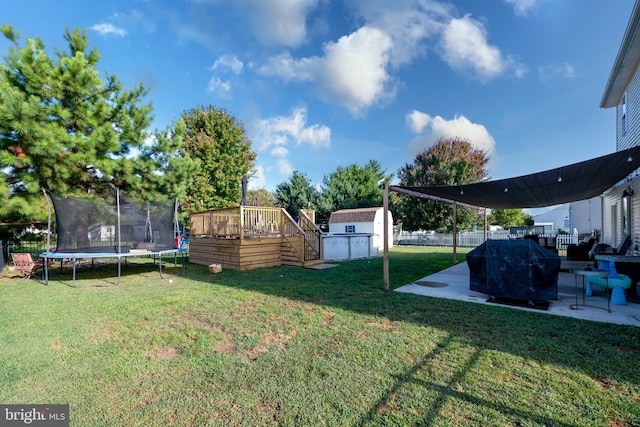 view of yard with a storage unit, a trampoline, a deck, and a patio