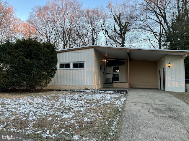 snow covered garage with a carport