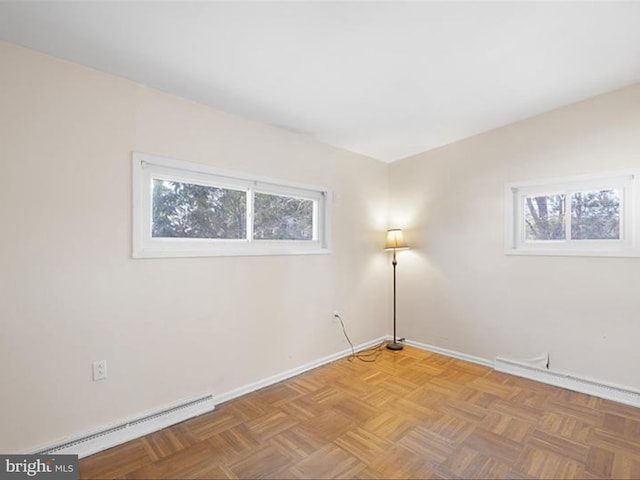 spare room featuring a wealth of natural light, light parquet flooring, and baseboard heating