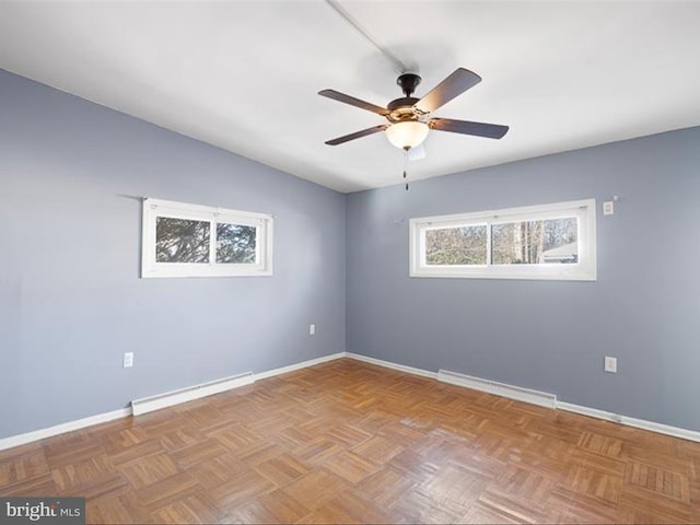 spare room with light parquet floors, ceiling fan, and a baseboard heating unit