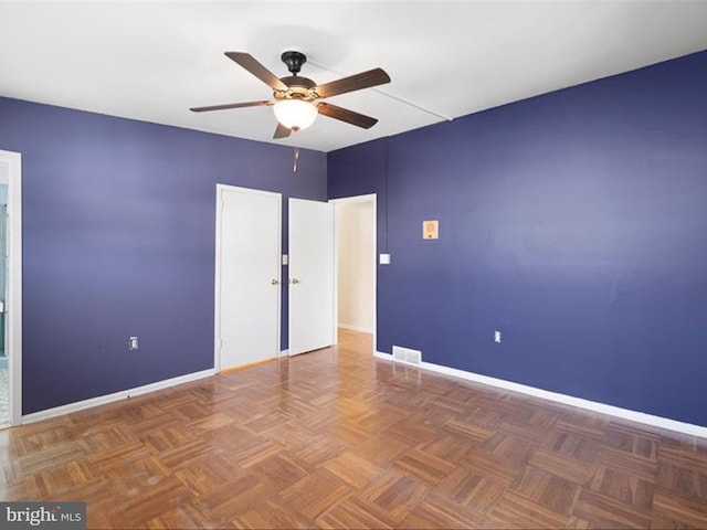 spare room featuring dark parquet flooring and ceiling fan