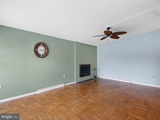 unfurnished living room featuring a large fireplace, parquet floors, and ceiling fan