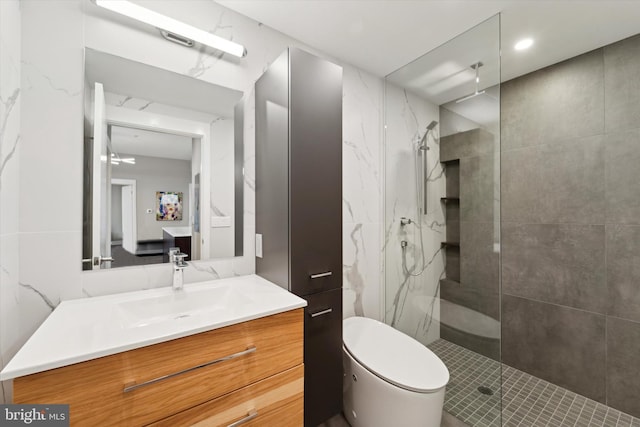 bathroom with a tile shower, vanity, and toilet