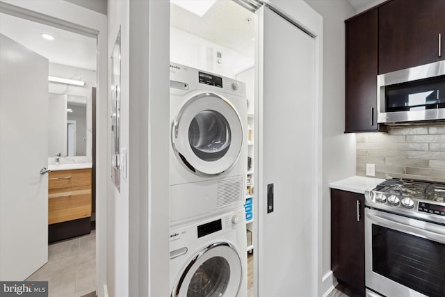 laundry room with light tile patterned floors, stacked washer / drying machine, and sink