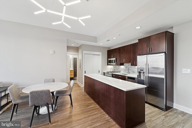 kitchen featuring a center island, tasteful backsplash, light hardwood / wood-style floors, dark brown cabinetry, and stainless steel appliances