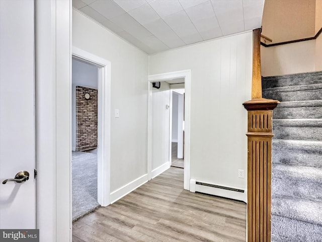 stairs featuring baseboard heating and hardwood / wood-style floors