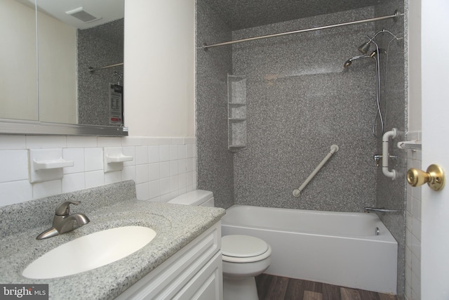 full bathroom featuring tile walls, tiled shower / bath combo, vanity, wood-type flooring, and toilet