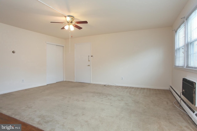 carpeted empty room with a baseboard radiator and ceiling fan