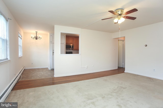 unfurnished room with hardwood / wood-style flooring, a baseboard radiator, a healthy amount of sunlight, and ceiling fan with notable chandelier