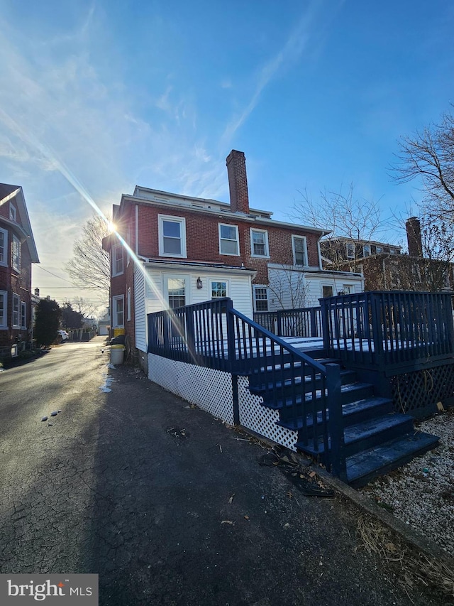 back house at dusk featuring a wooden deck