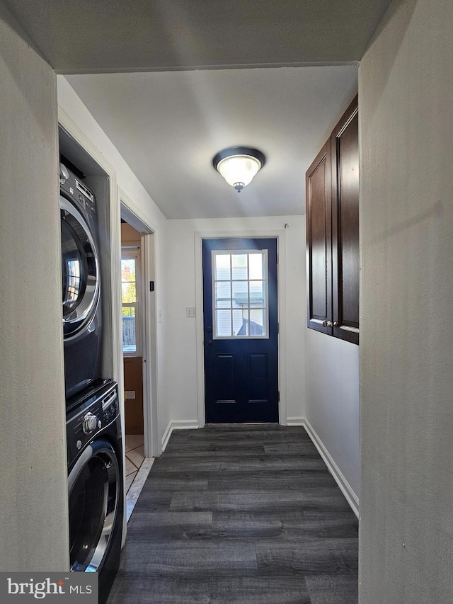 laundry area featuring dark wood-type flooring and stacked washer and clothes dryer