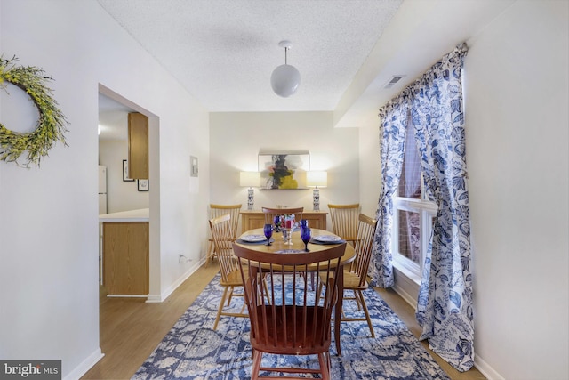 dining room with light hardwood / wood-style floors and a textured ceiling