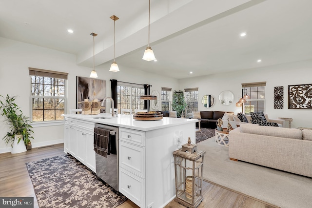 kitchen with sink, hanging light fixtures, stainless steel dishwasher, an island with sink, and white cabinetry