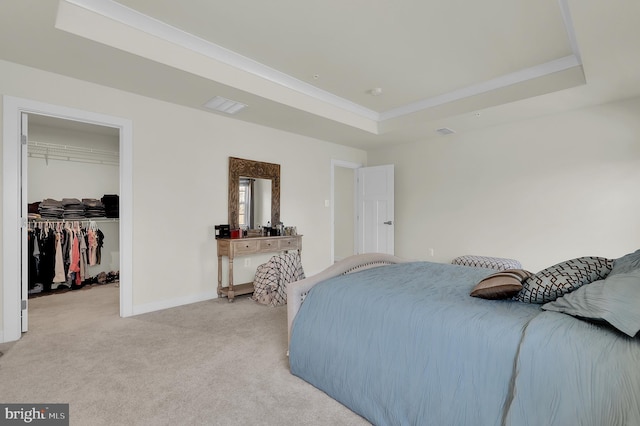 bedroom with light carpet, a tray ceiling, a spacious closet, and a closet