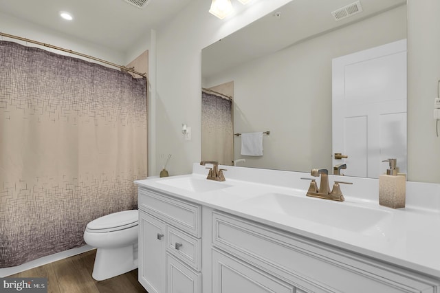 bathroom with a shower with shower curtain, hardwood / wood-style floors, vanity, and toilet