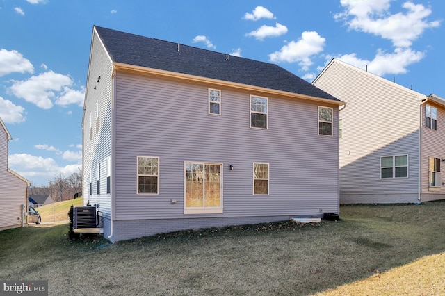 rear view of property featuring central AC unit and a lawn