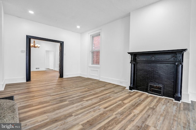 unfurnished living room featuring a notable chandelier and light hardwood / wood-style floors