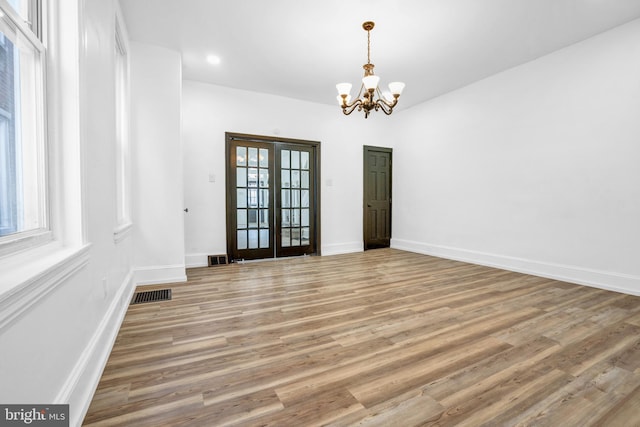 empty room with french doors, hardwood / wood-style flooring, and a notable chandelier