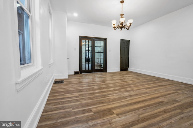 unfurnished room featuring a notable chandelier, dark hardwood / wood-style flooring, and french doors