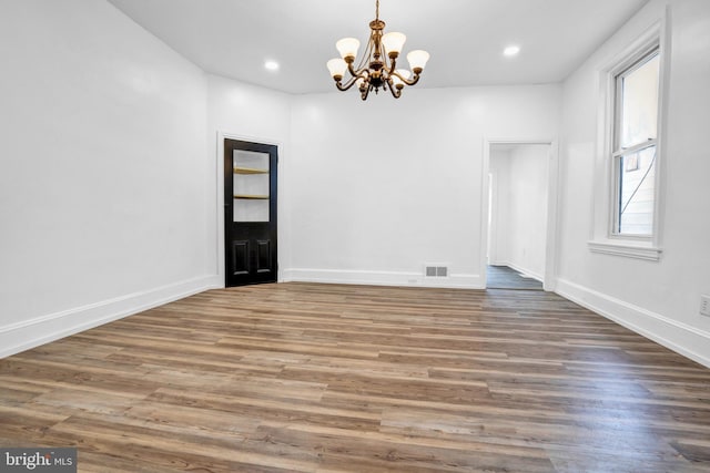 unfurnished room featuring dark hardwood / wood-style floors, a wealth of natural light, and a notable chandelier