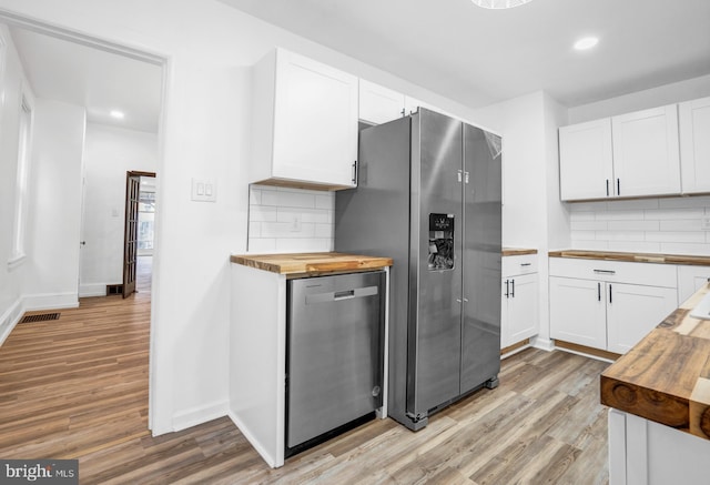 kitchen with butcher block countertops, white cabinetry, and stainless steel appliances