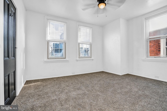 carpeted spare room featuring a wealth of natural light and ceiling fan