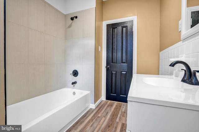 bathroom featuring tasteful backsplash, vanity, tiled shower / bath combo, tile walls, and hardwood / wood-style floors