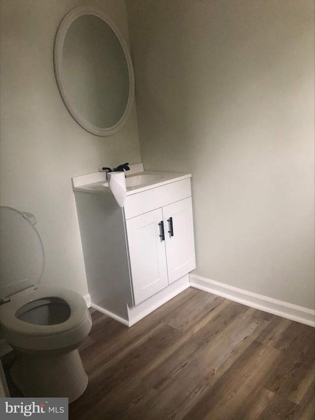 bathroom with toilet, vanity, and hardwood / wood-style flooring