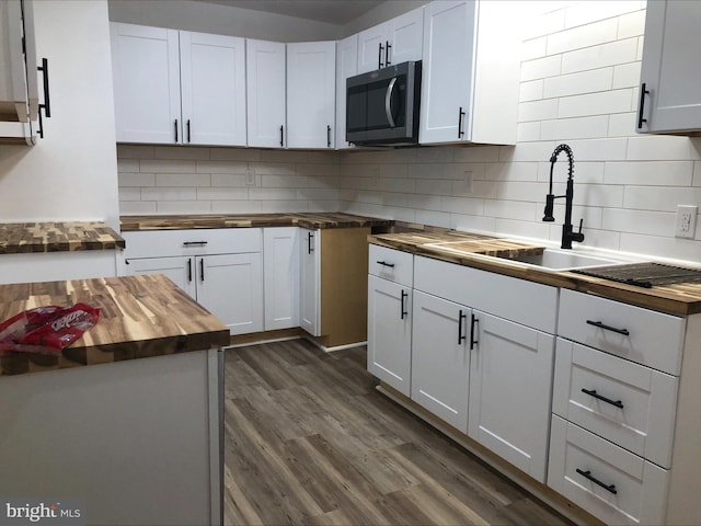 kitchen featuring butcher block counters, decorative backsplash, and white cabinets