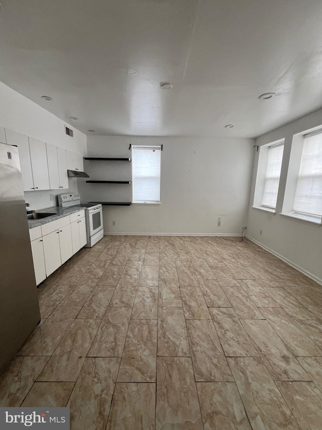 kitchen with white cabinets, white range with electric stovetop, plenty of natural light, and stainless steel refrigerator