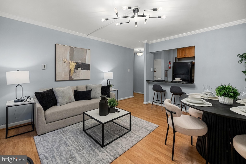 living room featuring a chandelier, crown molding, and light hardwood / wood-style flooring