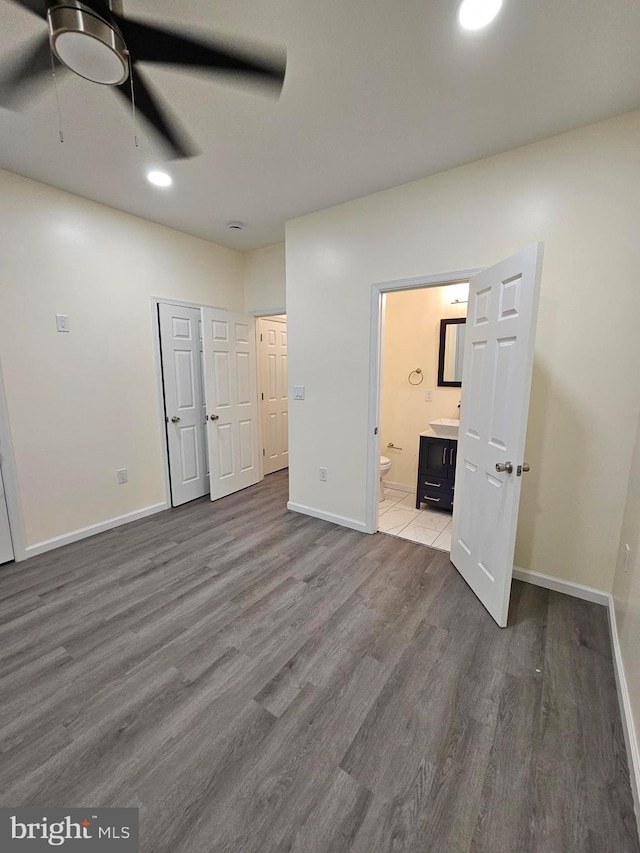 unfurnished bedroom with connected bathroom, ceiling fan, and hardwood / wood-style flooring