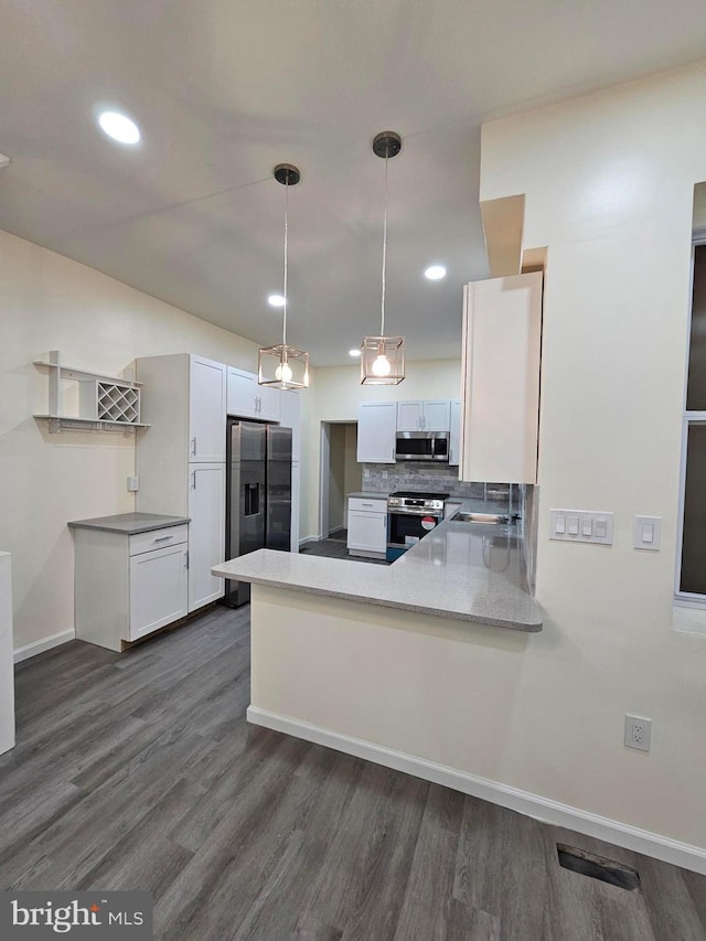 kitchen with kitchen peninsula, decorative backsplash, white cabinets, and stainless steel appliances