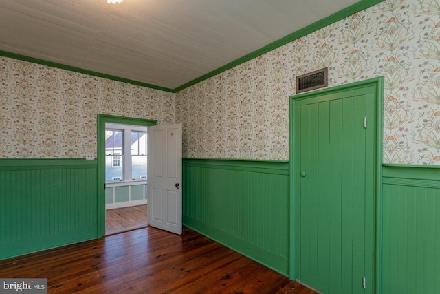 empty room with crown molding and dark wood-type flooring