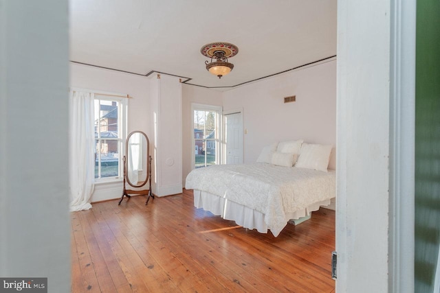 bedroom with multiple windows and hardwood / wood-style flooring